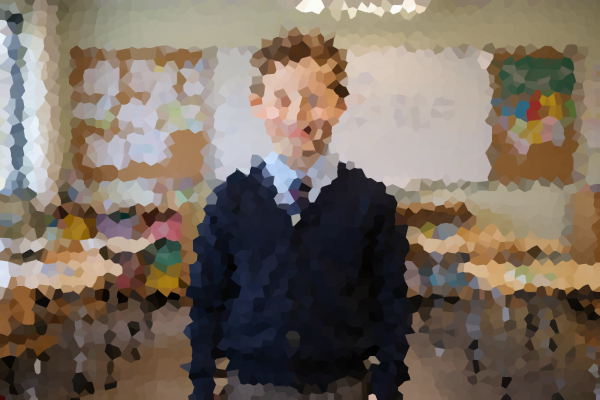 Pixelated photograph of a pupil in a school uniform standing in a classroom